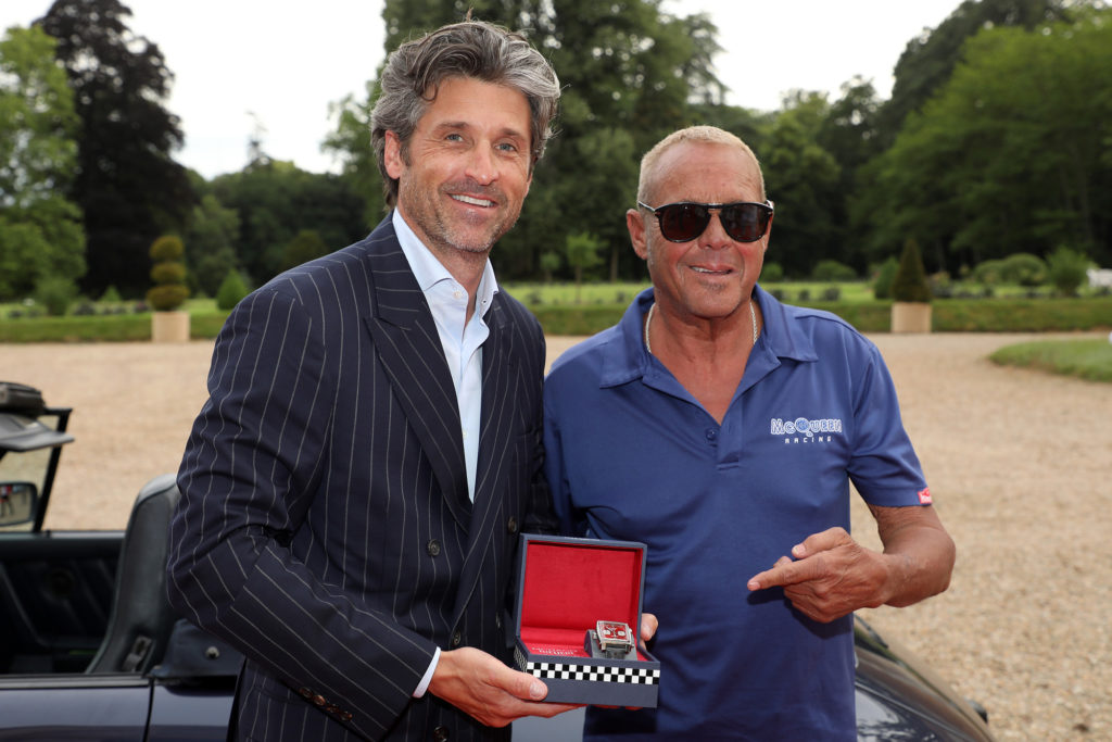 Patrick Dempsey and Chad McQueen stood together while holding a box containing a TAG Heuer Monaco watch.