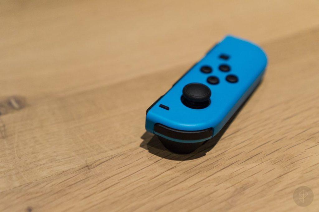 Blue Nintendo Switch Joy-Con on a wooden table.