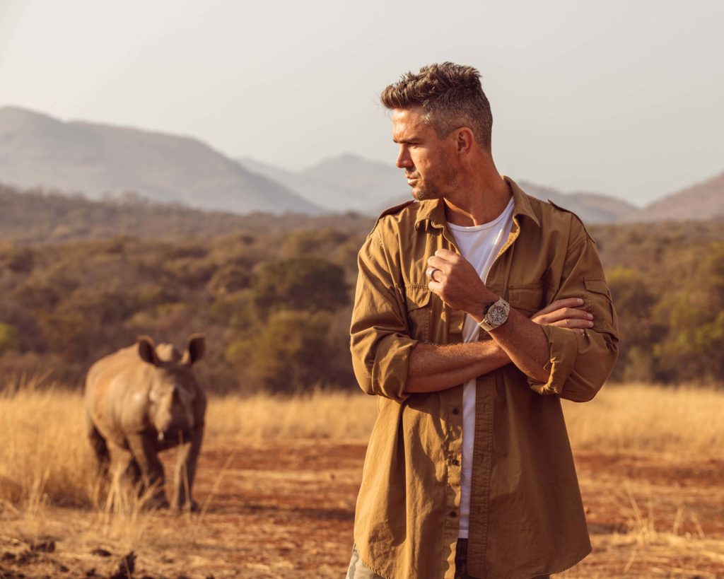 Kevin Pietersen stood in the serengeti with a rhino behind him.