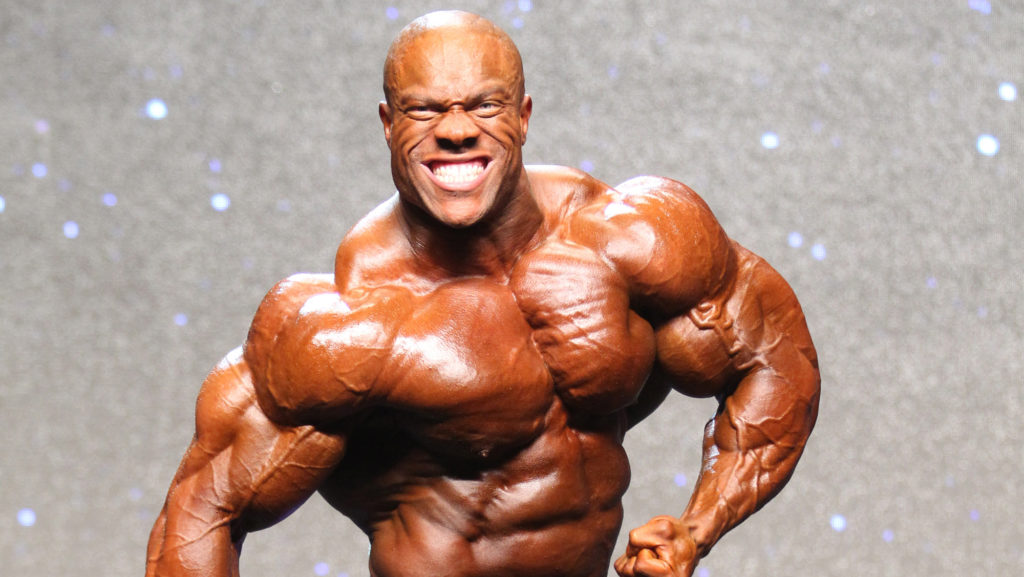 Phil Heath grinning while shirtless and flexing.