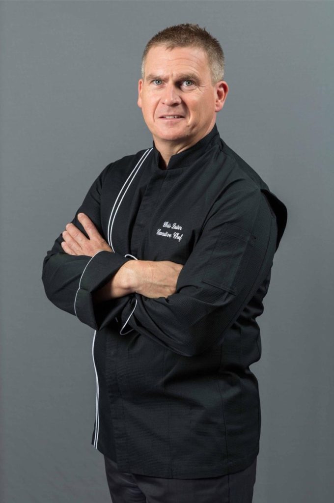 Chef Christopher Lester wearing black outfit with arms folded.